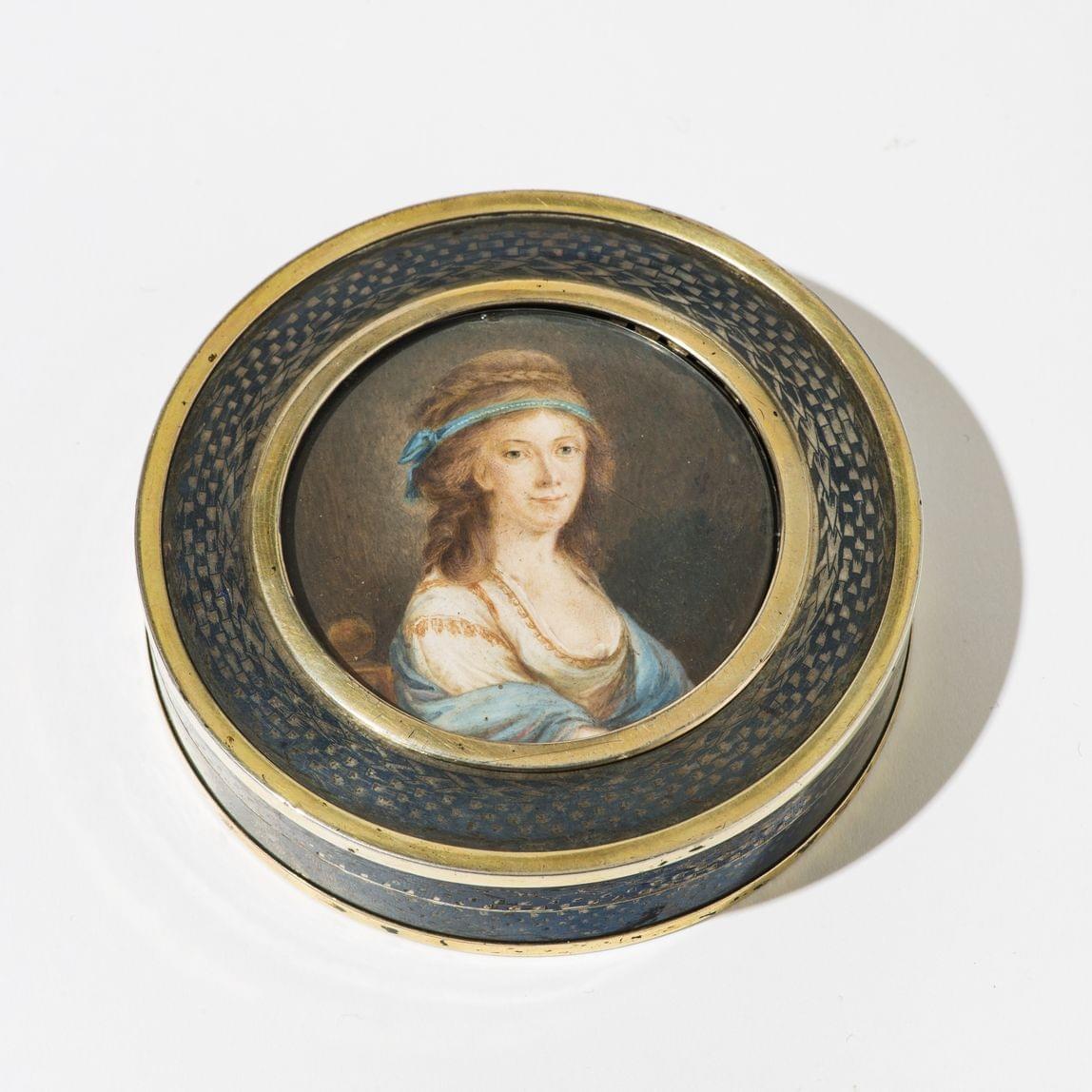 Boîte ronde d'époque néoclassique à décor finement niellé d'un trophée sur un fond imitant un tressage et ornée sur le couvercle d'une miniature de jeune femme portant un ruban bleu dans les cheveux